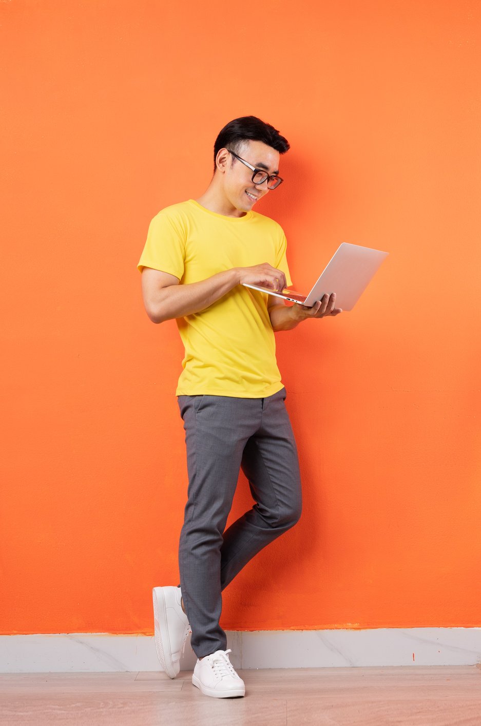 Full Body Photo of Asian Man in Yellow Shirt on Orange Background